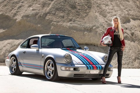 Young woman with long blonde hair poses with Porsche 911 Carrera 4