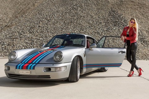 Young woman with long blonde hair poses with Porsche 911 Carrera 4