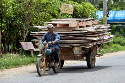 Man with moped and trailer transporting large wooden panels