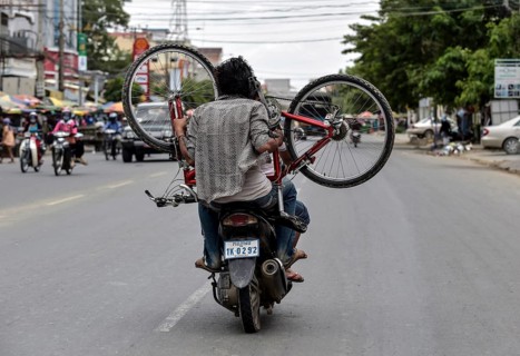 Man with moped carries a bicycle