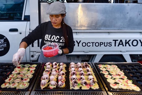 Woman sells baby octopus from grill at a food stall