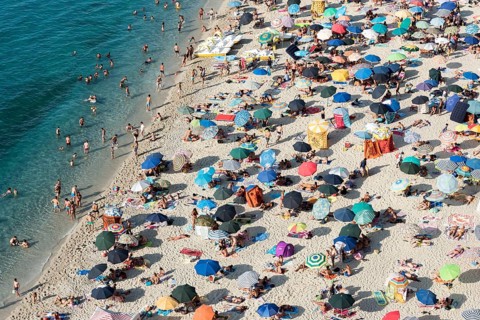 Many people with colorful sunshades at Tropea Beach