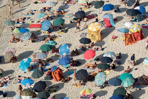Many people with colorful sunshades at Tropea Beach