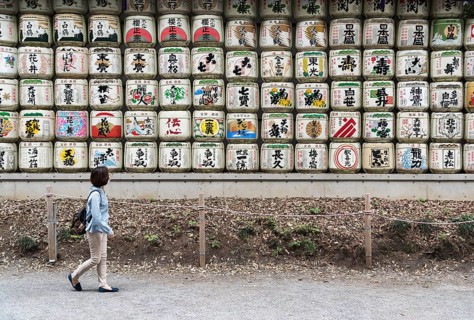 Woman walks pass sake barrels at Meiji Jingu Shrine