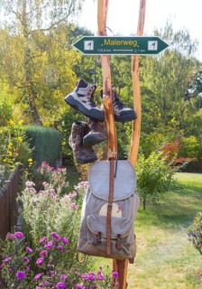 Sign Malerweg hiking trail with hiking boots and backpack in Daube near Lohmen