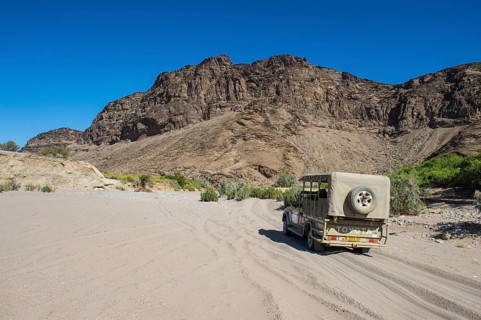 Tourist jeep driving through the deep sand searching for safari