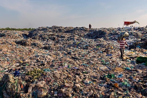 Garbage collector in garbage dump with plastic garbage
