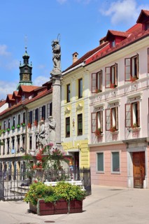 Nepomuk fountain in front of house facades on market square Mestni Trg with tower St. James' Church