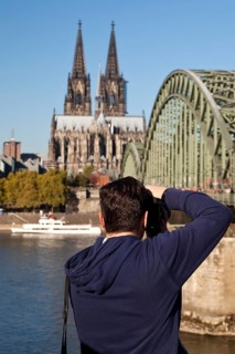 A man photographs Cologne Cathedral with the Hohenzollern Bridge