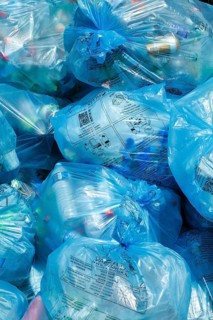 Full light blue garbage bags with plastic garbage on one heap