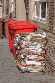 Red bins for waste glass and stacks of waste paper
