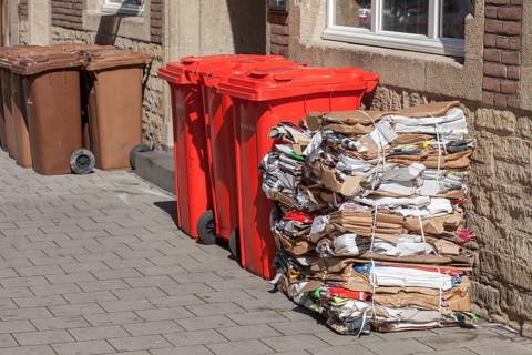 Red bins for waste glass and stacks of waste paper