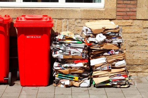Red bins for waste glass and stacks of waste paper