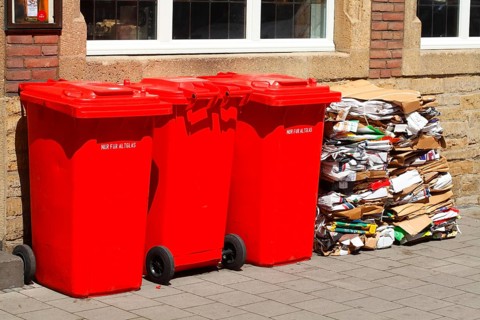 Red bins for waste glass and stacks of waste paper