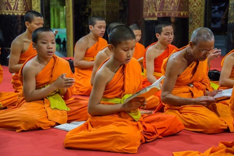 Buddhist monks praying in the temple Wat Xieng Thong