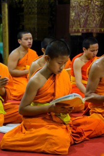 Buddhist monk praying in the temple Wat Xieng Thong