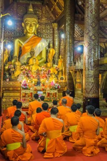Buddhist monks praying in the temple Wat Xieng Thong