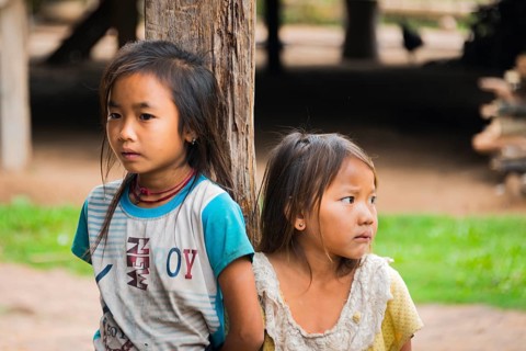 Two shy girls by a post of a hut