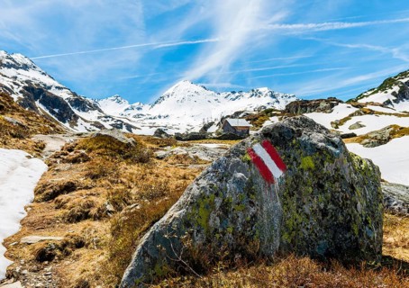 Red and white sign painted on rock marking hiking trail