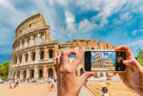 Hands of tourist photographing the Colosseum with smartphone