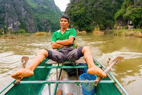 Local man rowing with his feet on the Ngo Dong River