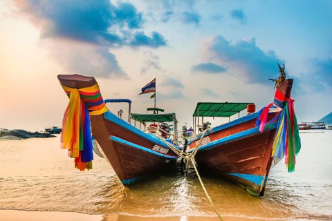 Moored colorful traditional long-tail boats on sandy beach