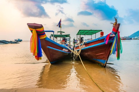Moored colorful traditional long-tail boats on sandy beach