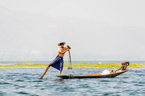 Local fishermen leg rowing on wooden boat