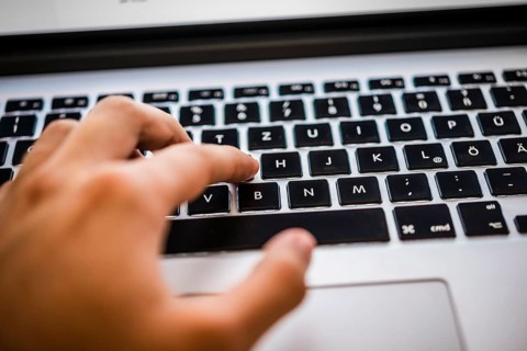Hand typing on MacBook Pro keyboard