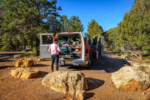 Young woman cooking at the gas stove of a camping van