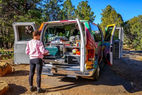 Young woman cooking at the gas stove of a camping van