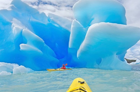 Kayaker heading for icebergs on lake
