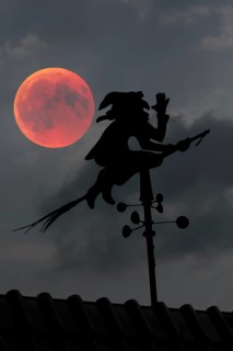 Blood moon over the roof of a house with weather vane with weather witch