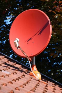 Red satellite dish on a roof of a residential house