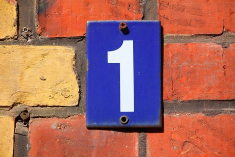 Blue house number plate number 1 on red brick wall
