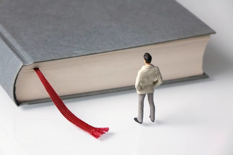 Male figure stands in front of grey book