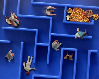 Different toy figures in a labyrinth looking for a way to the gold treasure