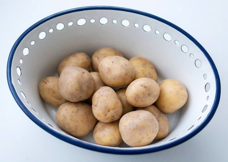 Raw potatoes in a bowl made of enamel