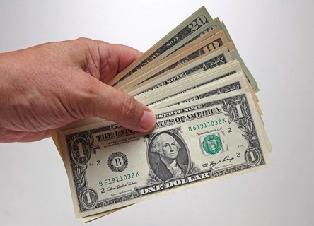 Hand holds bundles of U.S. dollars