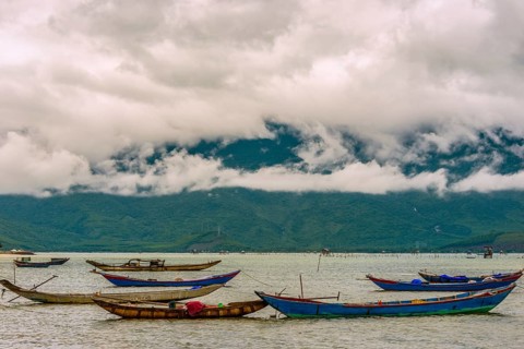 Fishing boats on sea at coast with dramatic stormy clouds in Hue