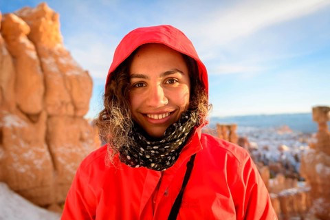 Portrait of a pretty young woman in winter clothes in front of rock needles
