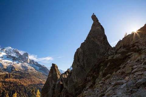 Climber standing on rocky pinnacle overlooking the mountains of Chamonix