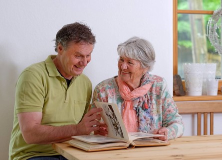 Grown-up son and elderly mother looking at a photo album