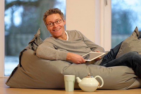 Man lying on large pillow with tablet