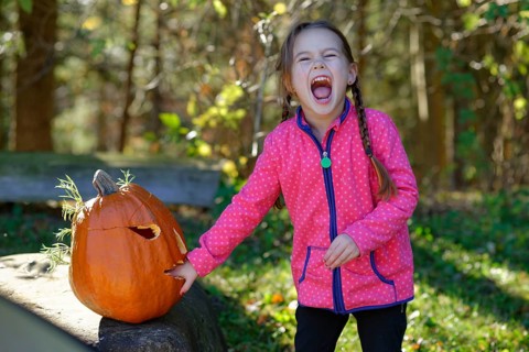 Girl with a Halloween pumpkin in autumn