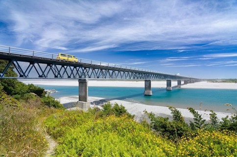 Yellow car driving over Haast River Bridge