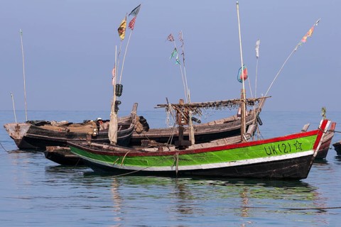 Colourful fishing boats in the sea off the beach of the fishing village of Ngapali