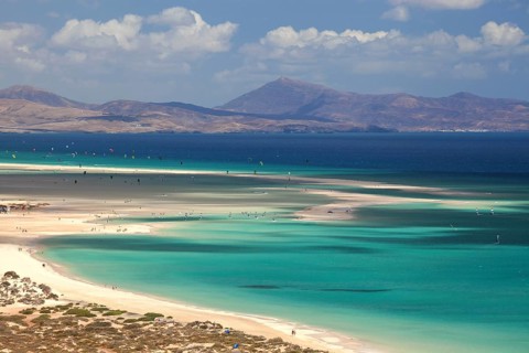 Beach and turquoise sea with windsurfers