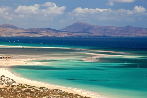 Beach and turquoise sea with windsurfers