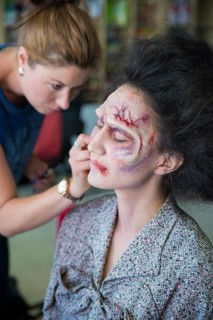 Actress being painted by makeup artist as a zombie for the zombie comedy Brain Freeze